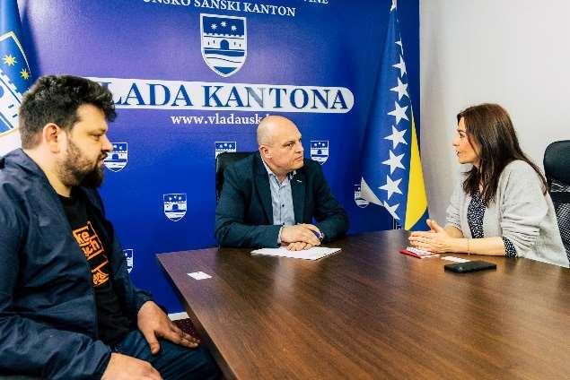 Petar Rosandić und Ewa Ernst-Dziedzic im Gespräch mit PRemiermenister Mustafa Ružnić an einem dunkelbraunen Holzdisch und vor einer blauen Wand nund der Flage von Bosnien Herzegowina.