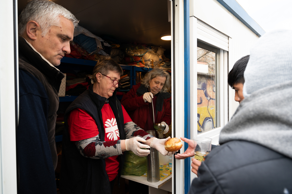 Menschen der Caritas schenken Suppe und Essen aus.