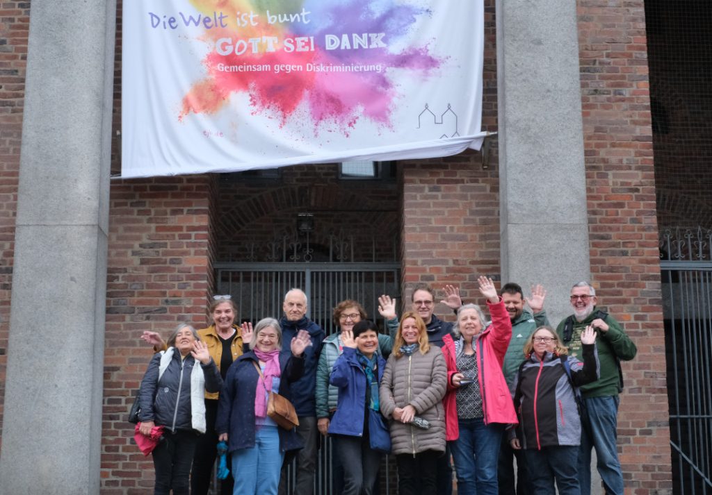 Gruppenfoto vor einem Banner der Evangelischen Jugend Bayern mit der Aufschrift: Die Welt ist bunt, Gott sei dank. Gemeinsam gegen Diskriminierung